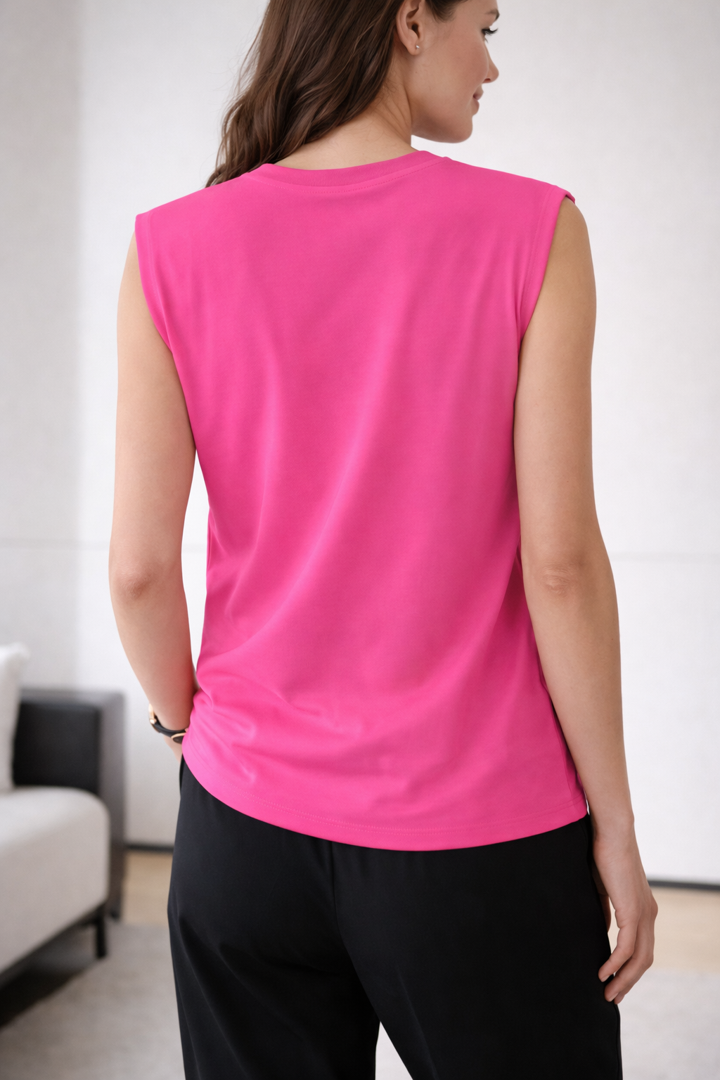 Female model wearing a pink sleeveless blouse. White background.