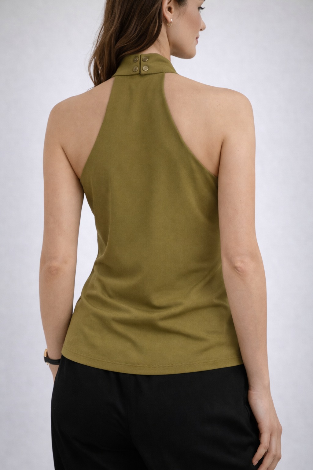Woman wearing a green sleeveless blouse.